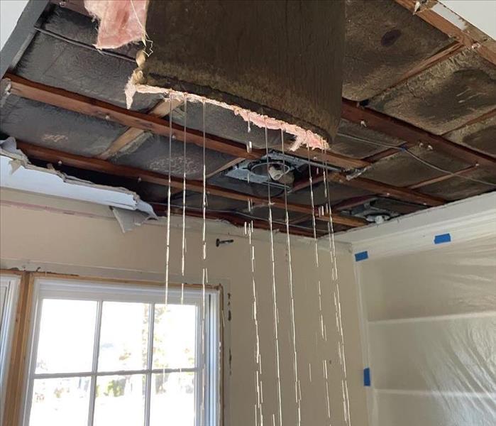 A ceiling cavity filled with wet insulation. Some of it is hanging down and leaking excessive amounts of water on the floor