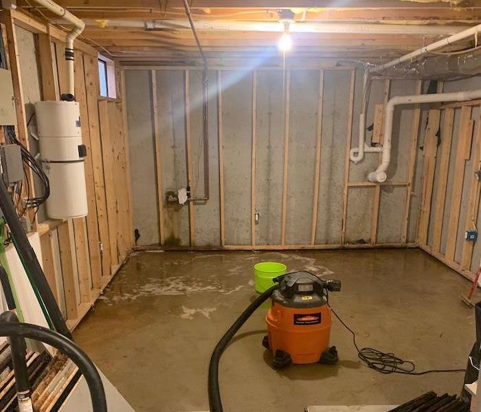 SERVPRO extraction equipment in basement with framework exposed