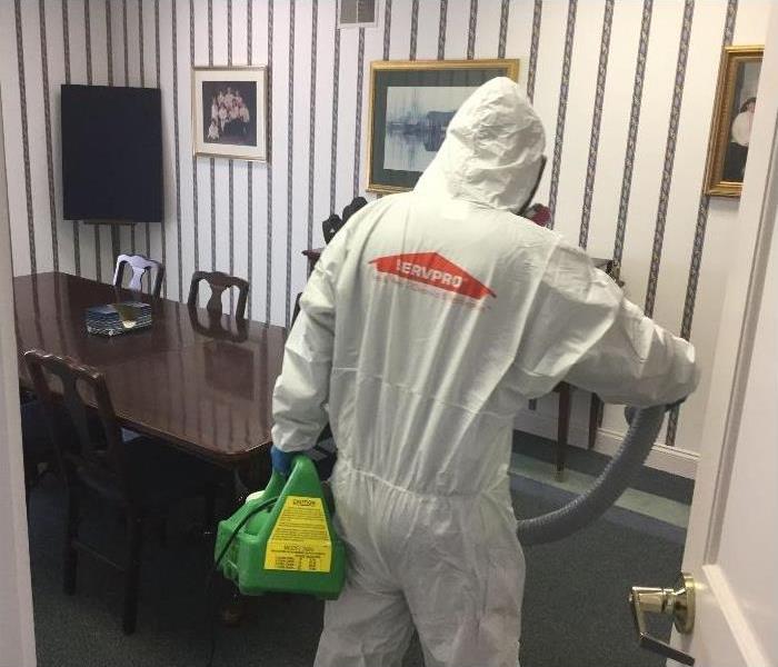 SERVPRO tech donned in PPE applying disinfectant in office