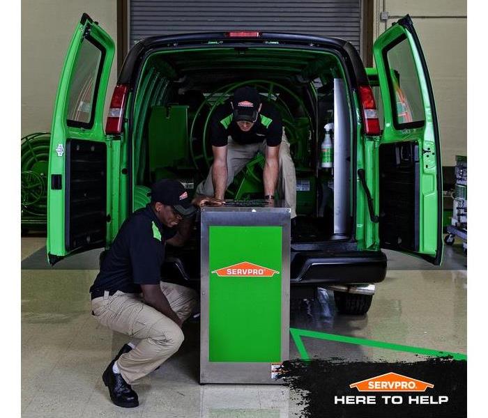 SERVPRO crew unloading equipment from SERVPRO van with the caption: SERVPRO, HERE TO HELP